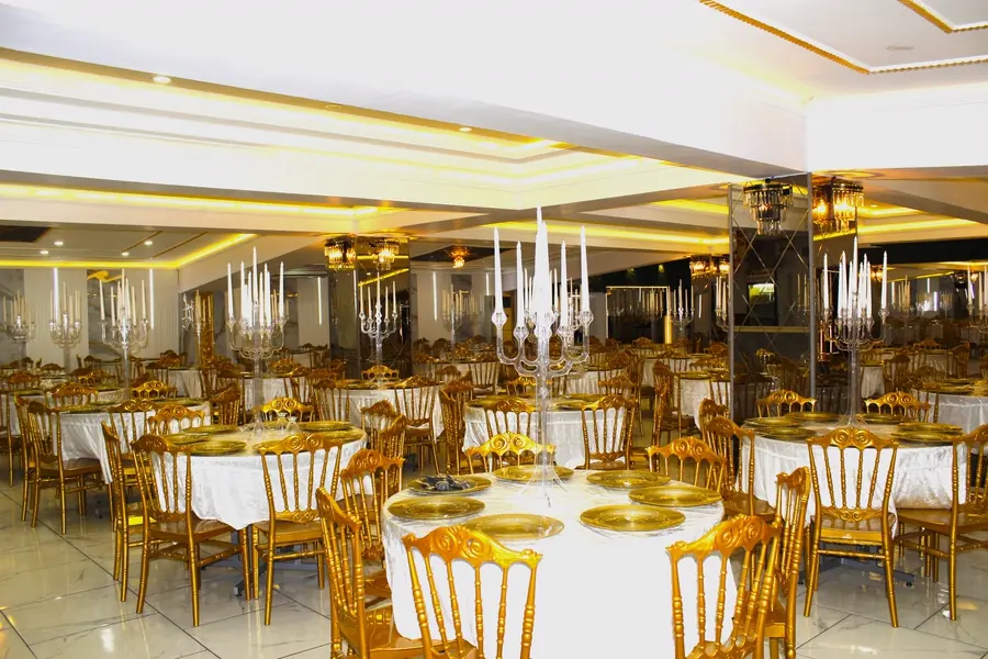 Yuvarlak masalar ve altın servis tabaklarıyla salon görünümü